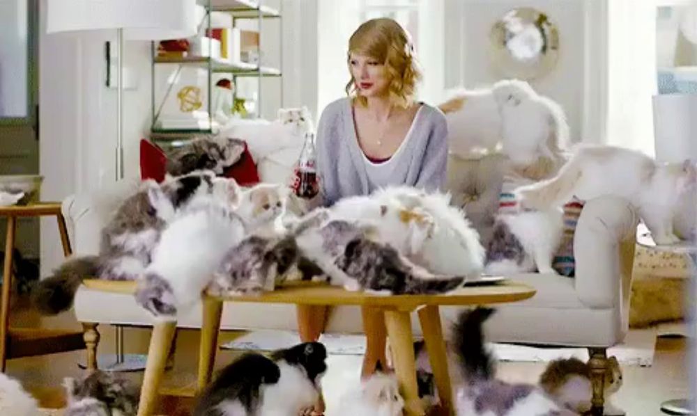 a woman sits at a table surrounded by kittens and a bottle of coca cola