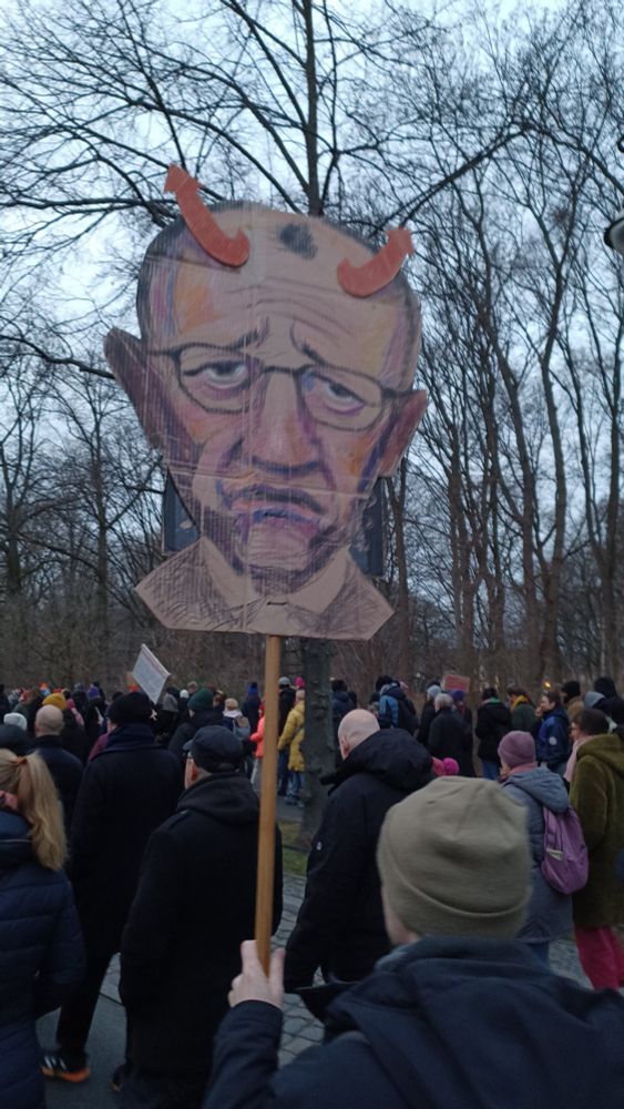 Demoplakat: Sehr gut getroffenes Kreideportrait eines sehr bedrömmelt dreinschauenden Friedrich Merz mit zwei roten AfD-Pfeilen als Teufelshörnchen. 