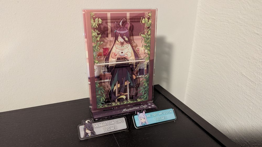 Two uma musume pins and a Manhattan Cafe acrylic stand