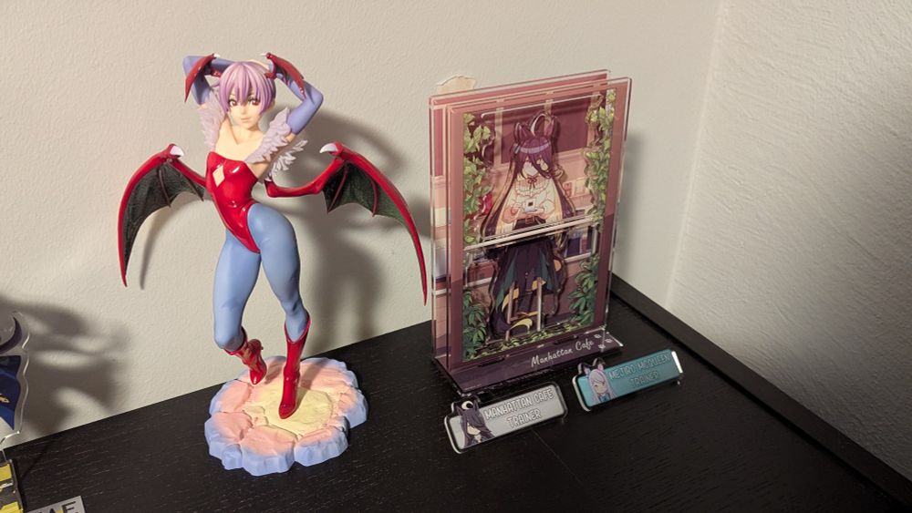 Two uma musume pins and a Manhattan Cafe acrylic stand size comparison with a Lilith scale figurene 