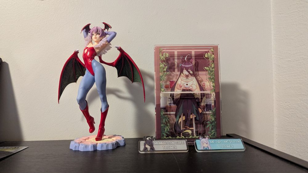 Two uma musume pins and a Manhattan Cafe acrylic stand size comparison with a Lilith scale figurene
