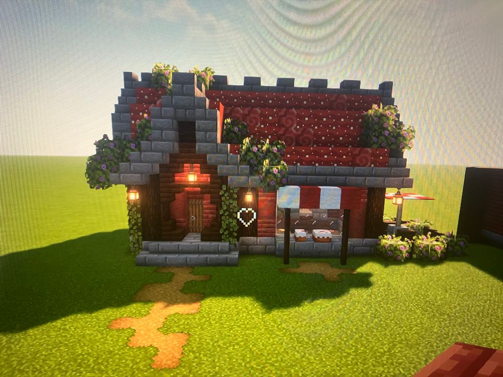 a bakery i built in minecraft. it has a stone foundation with walls made of mangrove and a roof made with mushroom blocks. it has spruce and dark oak accents and a display window for a cake. 