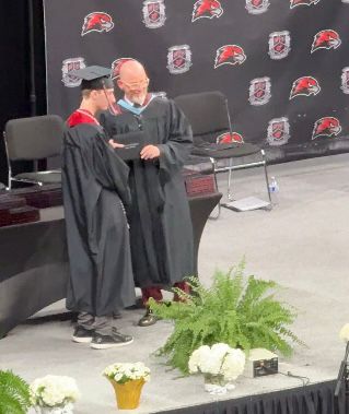 A student in cap and gown receiving a diploma
