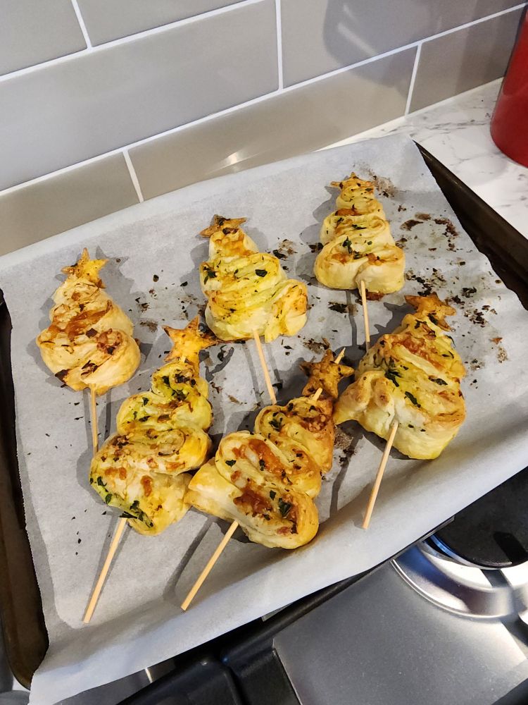 Paired 3cm strips of puff pastry filled with garlic butter and cheese, folded on their sides into a Christmas tree shape, slathered with more garlic butter and cheese and baked until crisp and puffed and golden, then skewered bottom to top. On the top of the skewer (and the tree) is a puff pastry star.