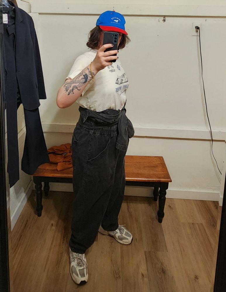 Morgan in the black denim jumpsuit, the top half has been removed and the arms are tied at her waist 