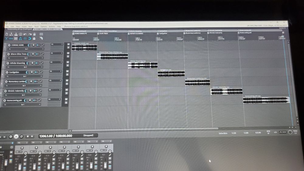 A photo of a computer screen showing the Reaper music software. There are seven tracks in the workspace, the seven tracks of the Homecoming album from MiseryFields.