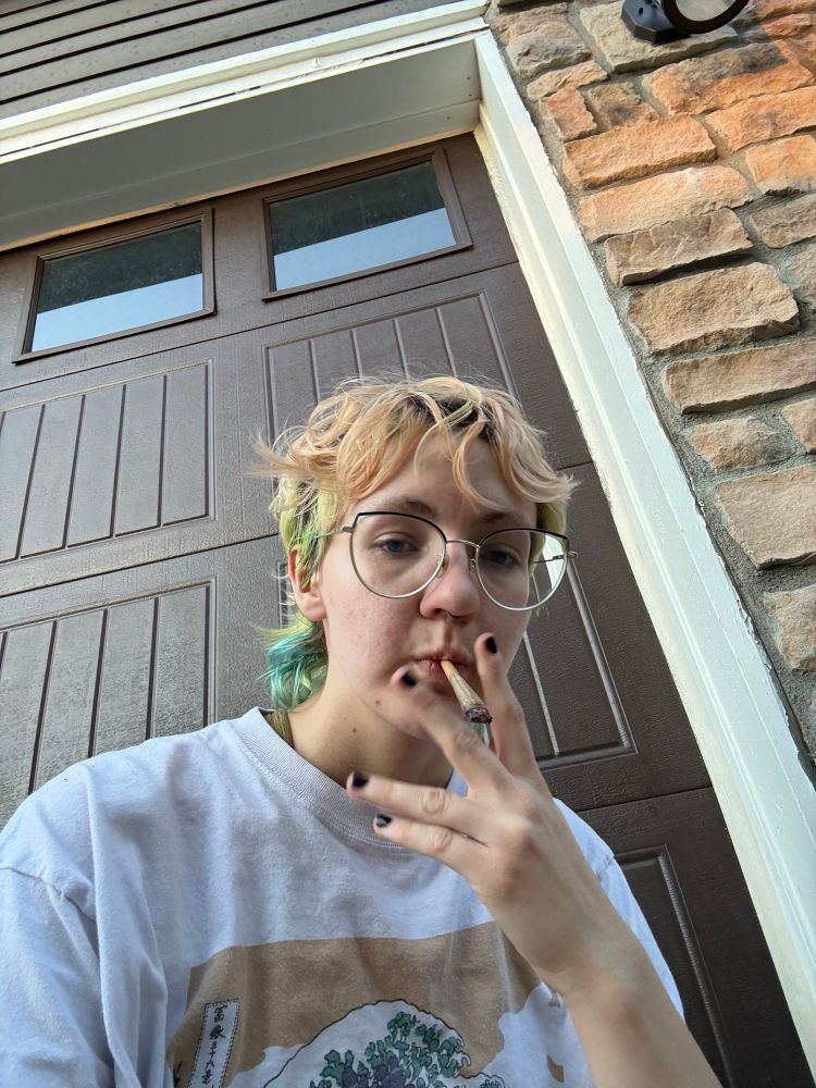 sable in a white graphic tee smoking a j in front of a garage door