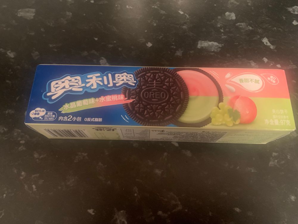 A packet of Oreo biscuits with Chinese writing . They are peach and grape flavour which I think sounds good. 
