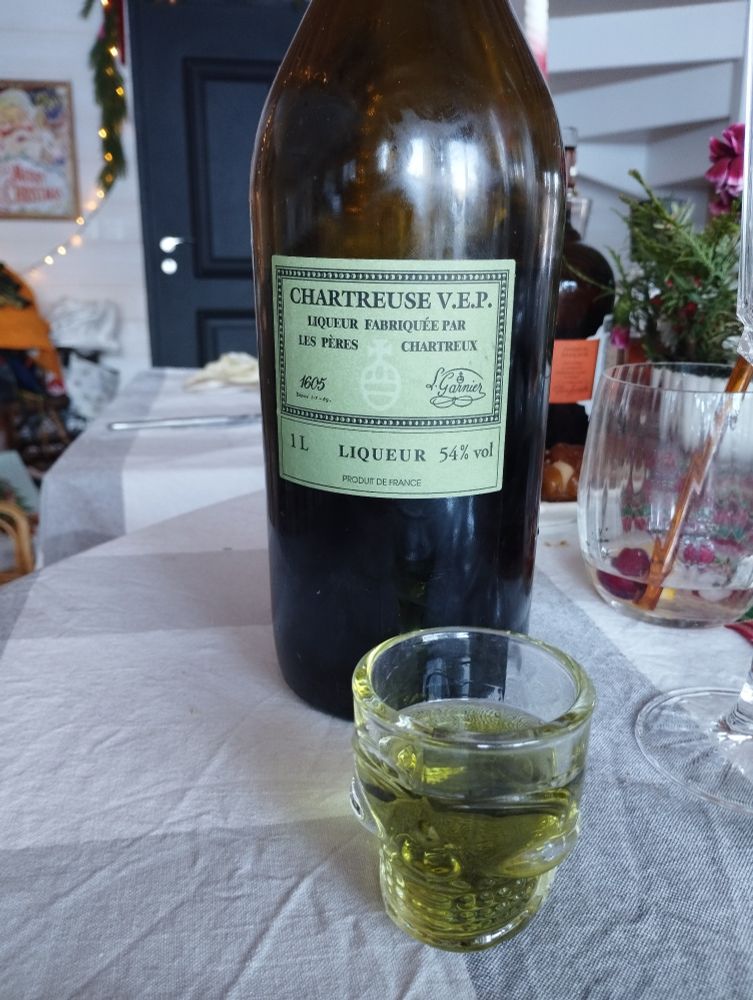 Un verre de shooter de Chartreuse VEP devant sa bouteille sur une table de Noël 