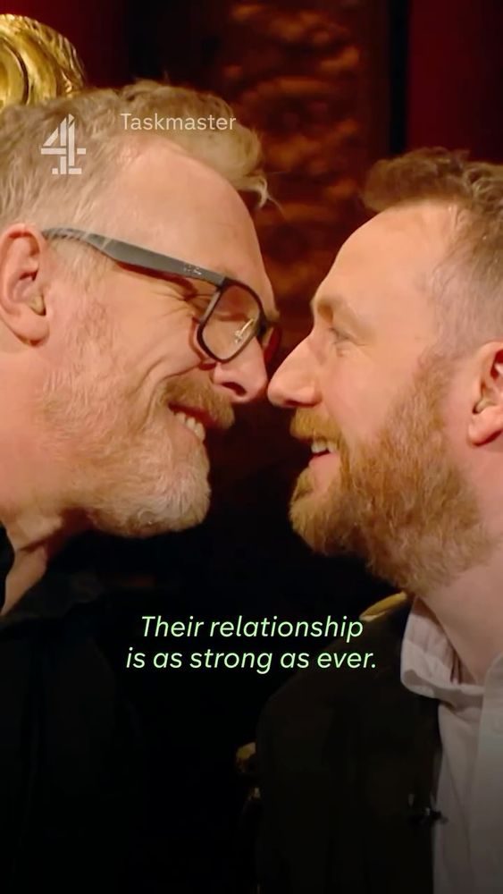 An image of Greg and Alex from Taskmaster, leaning in toward each other and about to kiss, with the caption: “Their relationship is as strong as ever.”