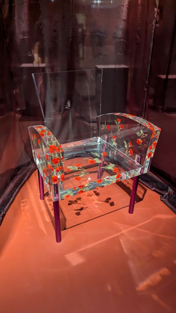 A clear resin armchair with roses embedded in the arms and seat.