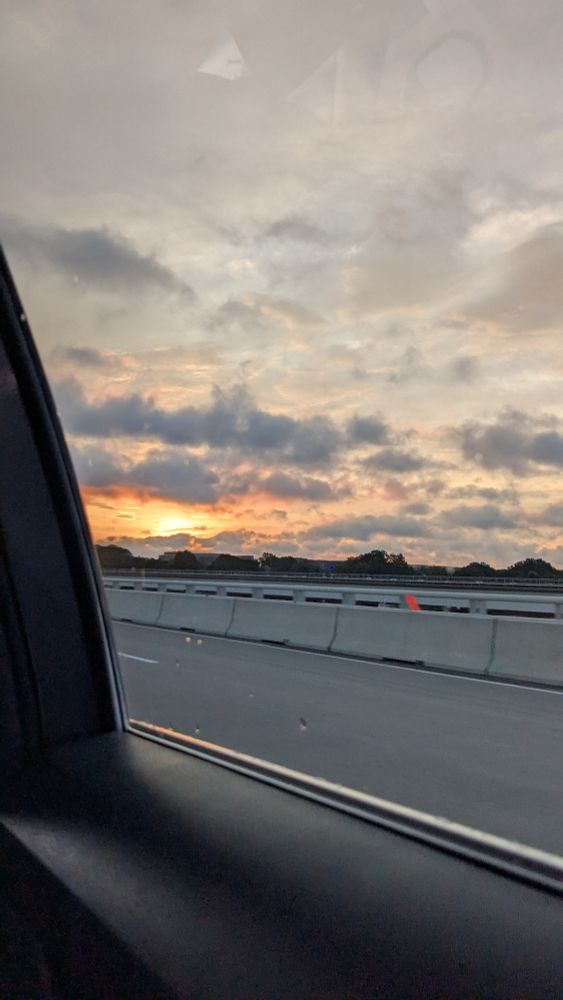 A sunrise through the clouds on a bridge taken through a car window