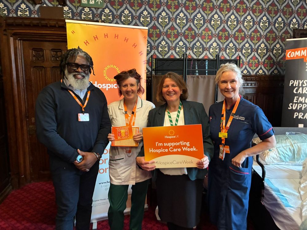 Ellie smiling with hospice staff in Parliament. Ellie is holding a sing which reads "I'm supporting Hospice Care Week"