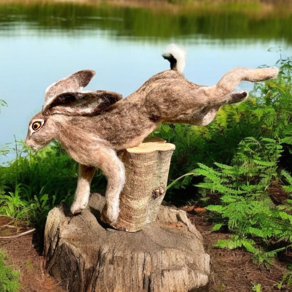 Wool sculpted leaping hare jumping over a log which is the mount for the sculpture.  