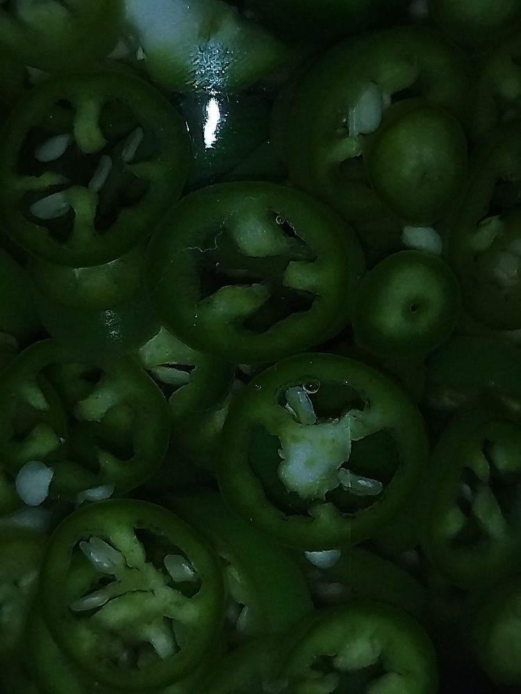 close up of green chillies on vinegar