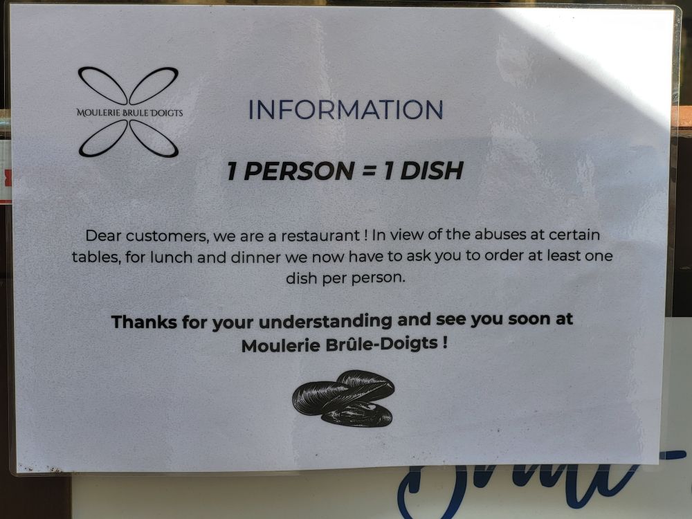 Pannonceau en anglais sur une ardoise de restaurant informant les clients indélicats qu'il convient de commander au moins un plat par personne.