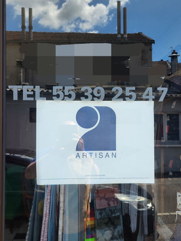 Photographie d'une devanture de boutique (de tapissier) avec un numéro de téléphone à 8 chiffres. La numérotation à 10 chiffres date de 1996.