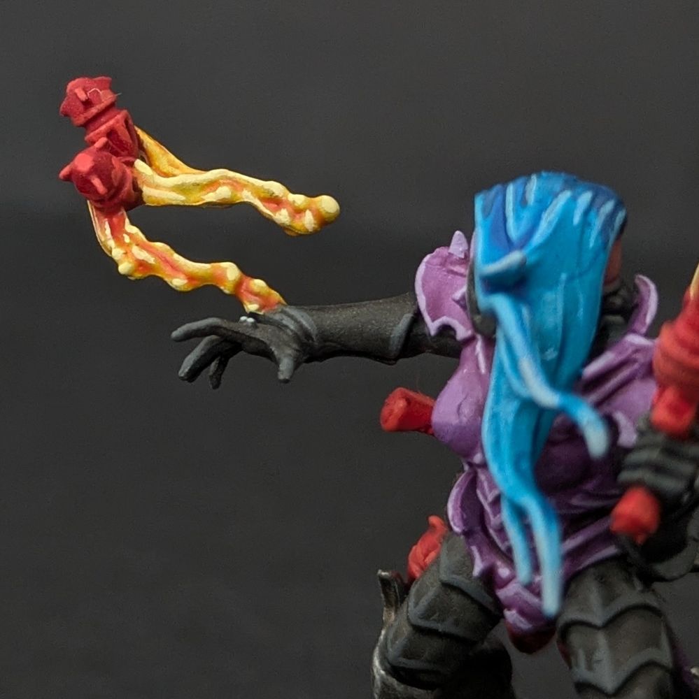 Close up of a member of the Hand of the Archon kill team squad. The colour scheme shows purple armour, red weaponry and blue dyed hair.