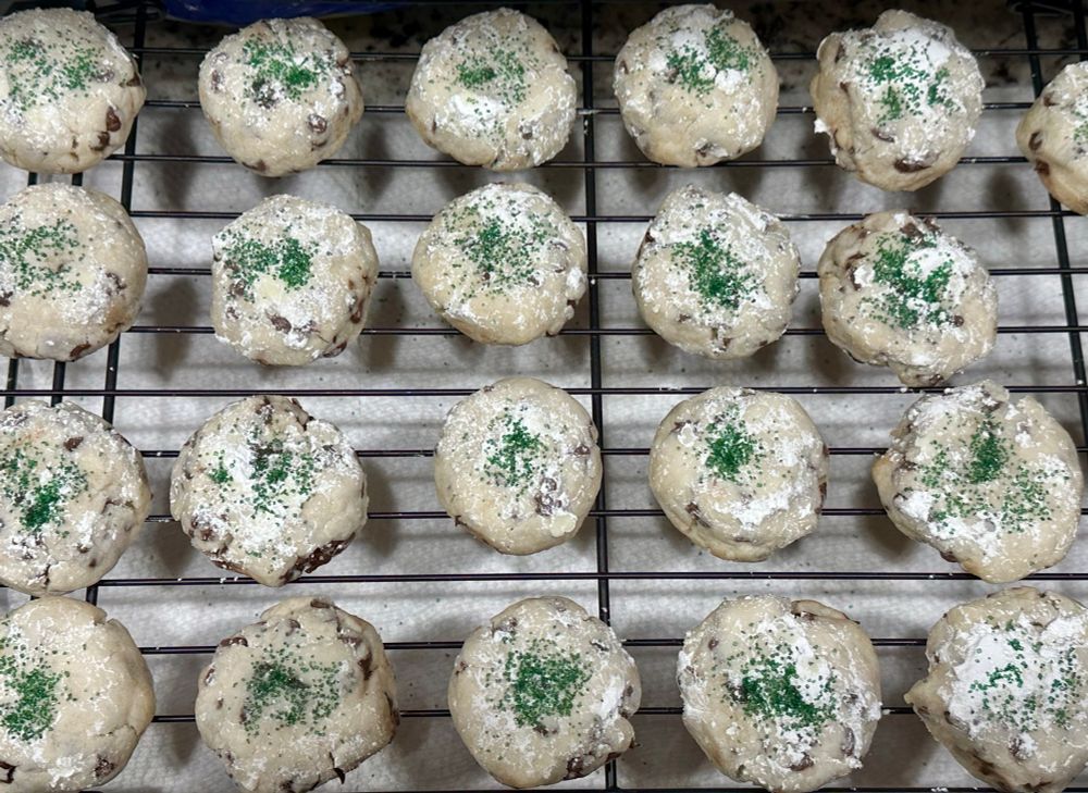 Rows of cookies topped with powdered sugar and green sugar sprinkles 