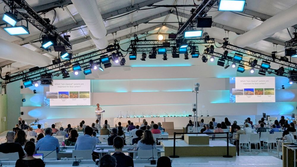 Large presentation hall with presenter and slides at the front
