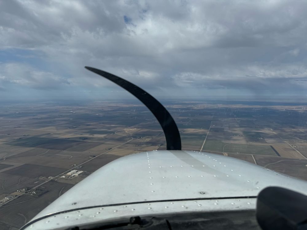 View from the cockpit of a small general aviation aircraft looking over fields. 