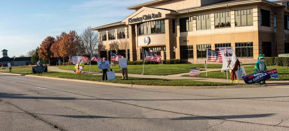 Intrepid Protester & group of resisters at "Moran Do Your Job" outside (and inside) his office Olathe KS [ Country Club Bank ]
signs & American flags RELEASE THE EPSTEIN FILES - NO KINGS IN AMERICA
- inflatable frog