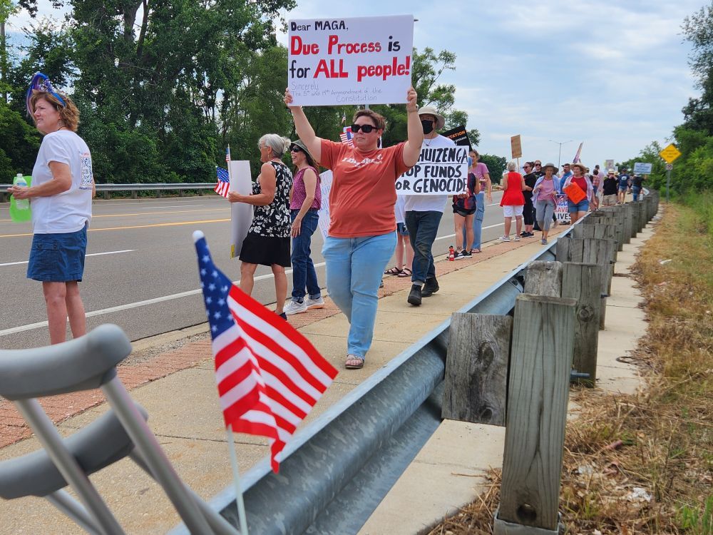 protesters in front US Rep. Bill Huizenga office Kalamazoo Portage
signs DUE PROCESS IS FOR ALL PEOPLE & American flag
