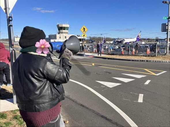 Avelo protesters at Tweed New Haven Regional Airport CY
-holding a bullhorn