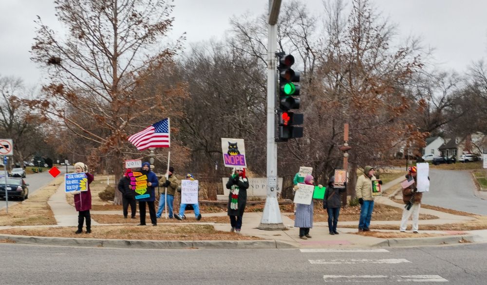 Intrepid Protester on street corner with weekly group at Roeland Park KS
signs & American flag VOTE - RESPECT THE VETERANS - RESIST