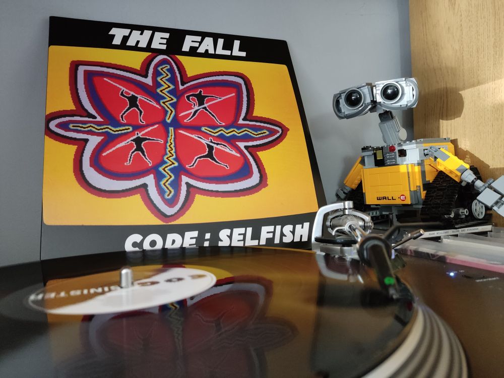Code: Selfish by The Fall. A black vinyl LP on a Stanton turntable. Lego Wall-E looks on from the right of the picture.