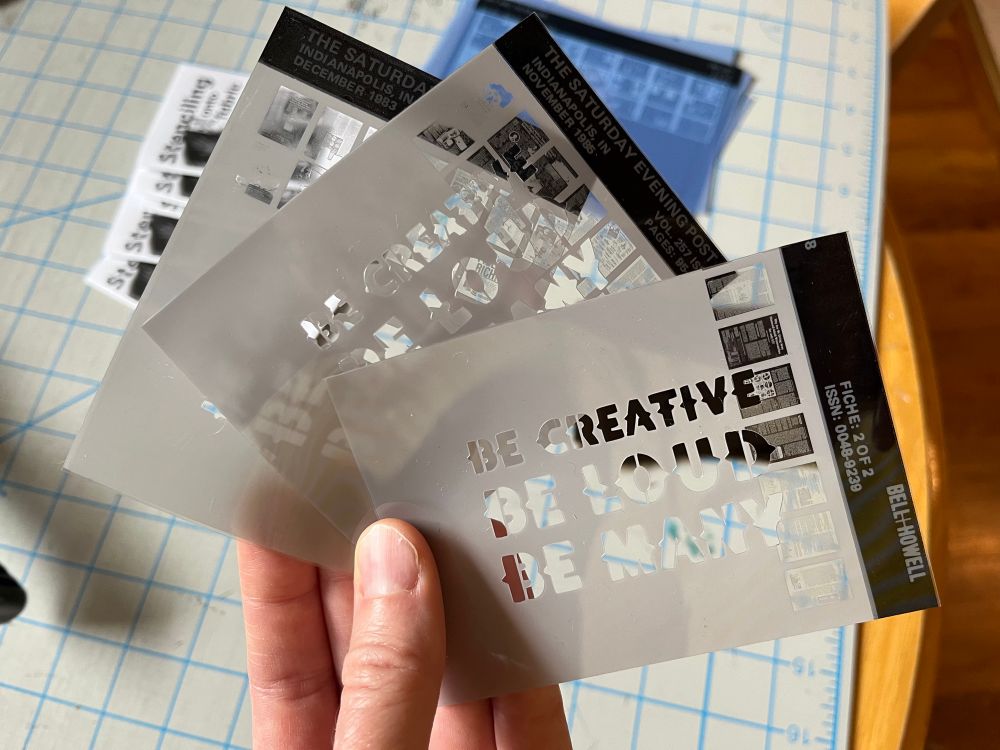 Stencils with the words BE CREATIVE BE LOUD BE MANY cut into film material