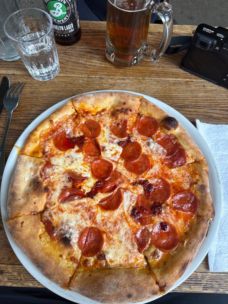 A 12 inch pepperoni pizza on a wood table outside in soho New York City