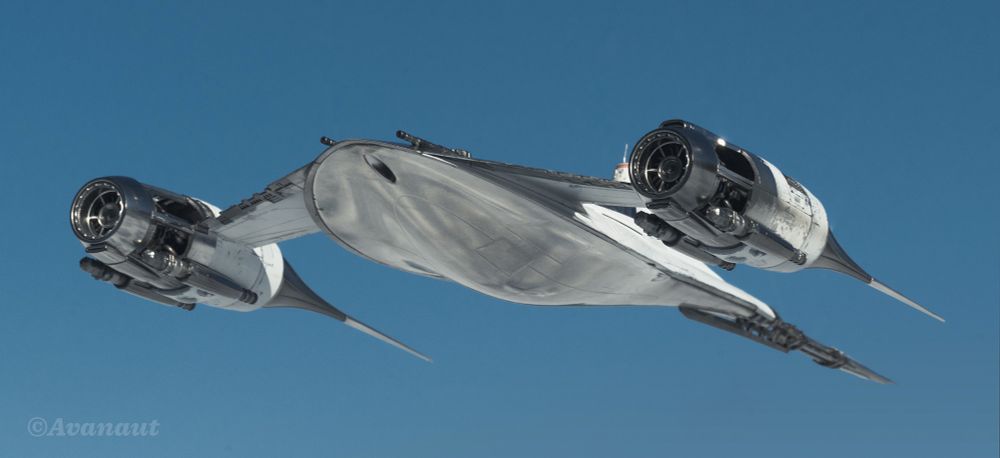 A white Naboo/Mandalorian N-1 starfighter photographed outdoors on a sunny say against blue sky. Low angle, below eye level, front quarter view. 
