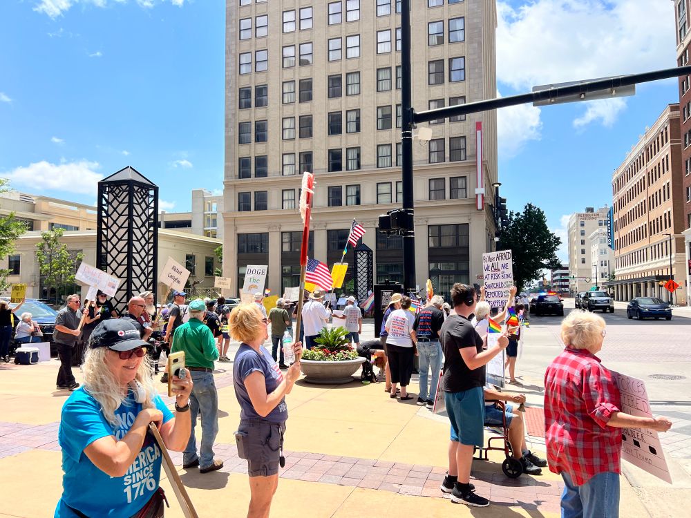 Demonstrators on downtown street corners holding signs protesting the Trump administration in Wichita, Kansas. 