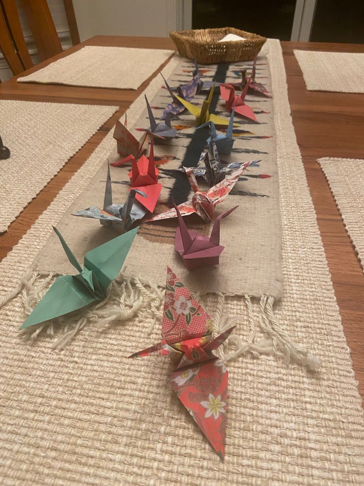 A dining table covered with folded origami peace cranes.