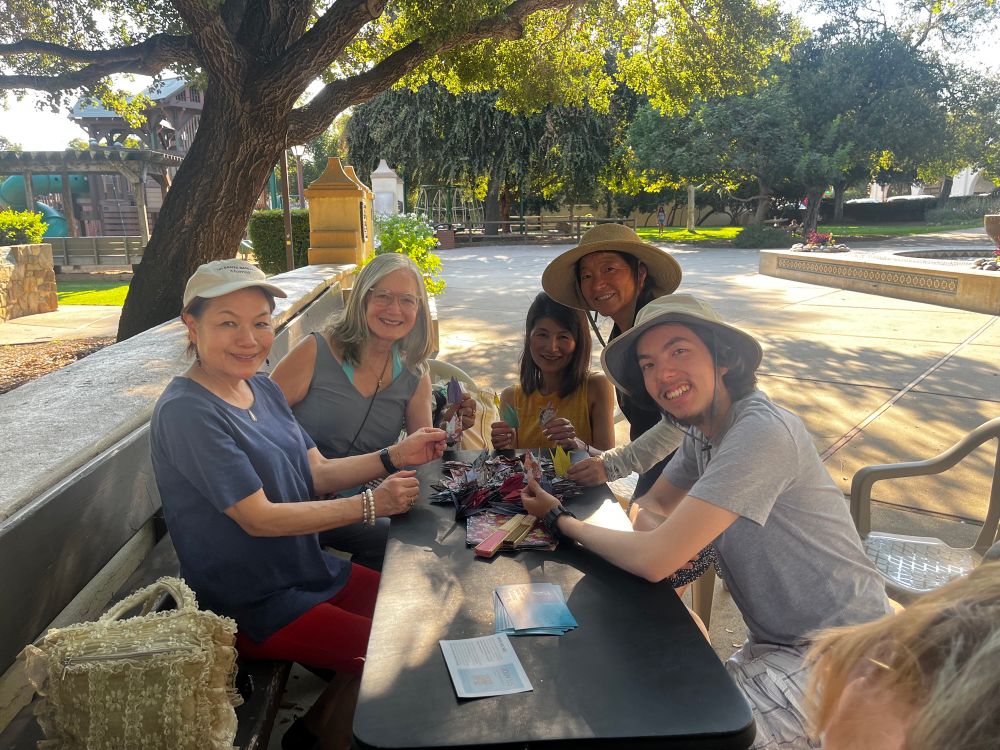 One group of people sitting around a table with all the cranes they had folded.