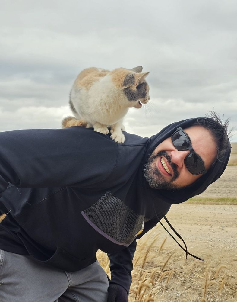Cat on smiling guy's back in cornfield