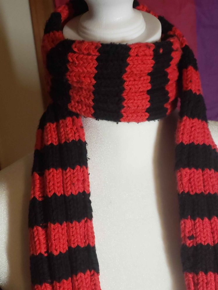 A black and red knitted rib scarf displayed on a mannequin
