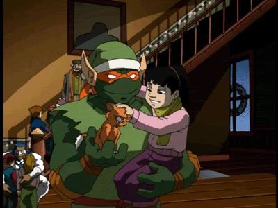 Michelangelo dressed as an elf holding an orphan as she pets Klunk the orange cat on his other hand in Teenage Mutant Ninja Turtles (2003) Season 3, Episode 1: "The Christmas Aliens."