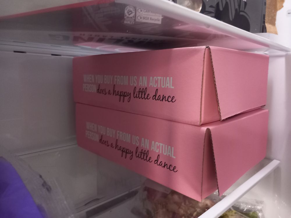 Two large pink boxes taking up the shelf of a fridge
