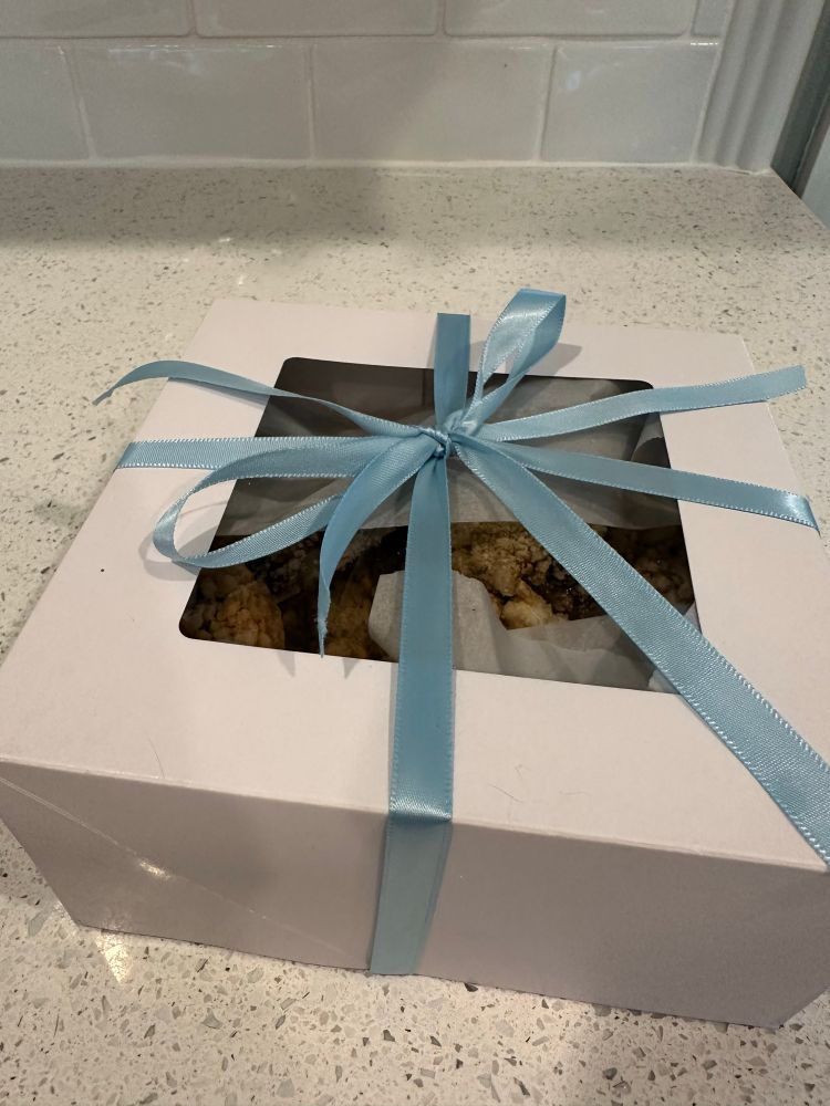 Closed white gift box with scones inside. Tied with a light blue ribbon
