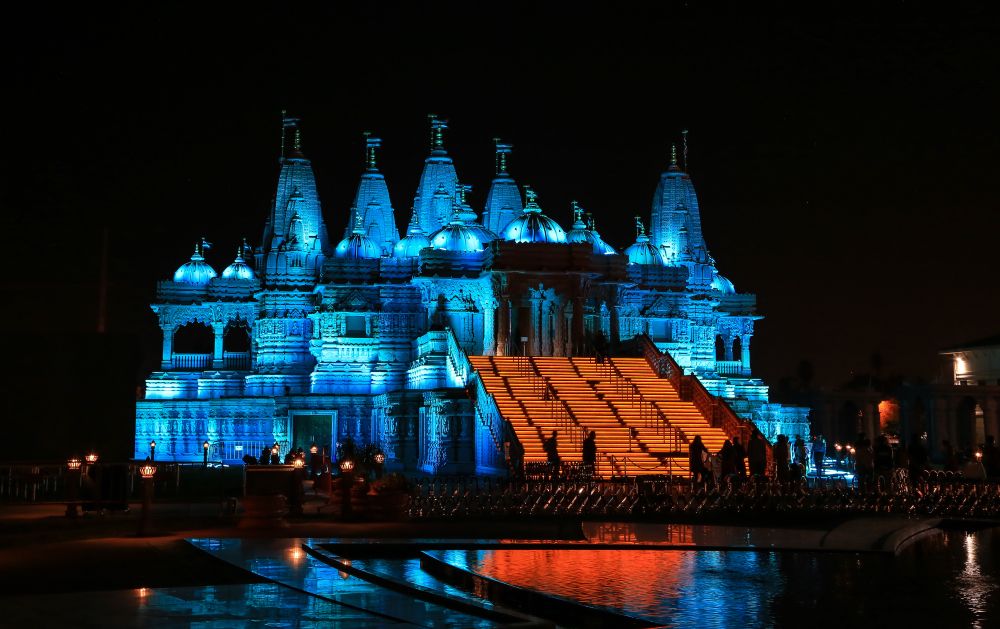 BAPS Temple mandir illuminated at night with blue lights and orange stairway during the Diwali festival celebration in Chino Hills, California