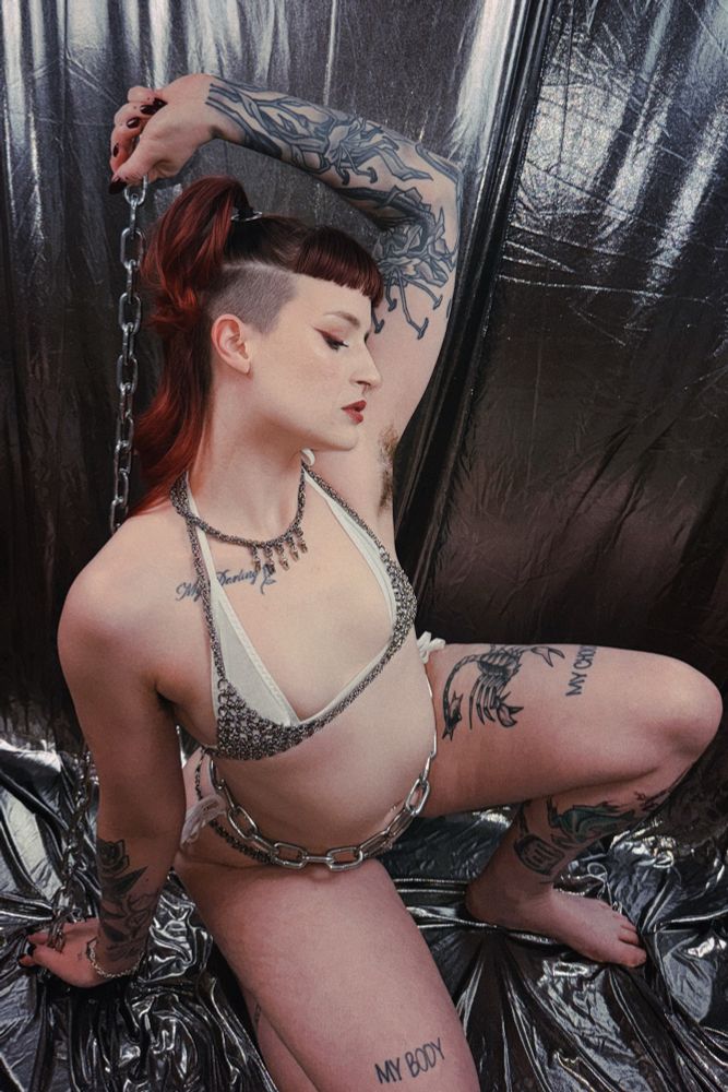 Stevie wearing a chainmaille bikini with a white bikini under it, a chain belt made of heavy hardware store chain,