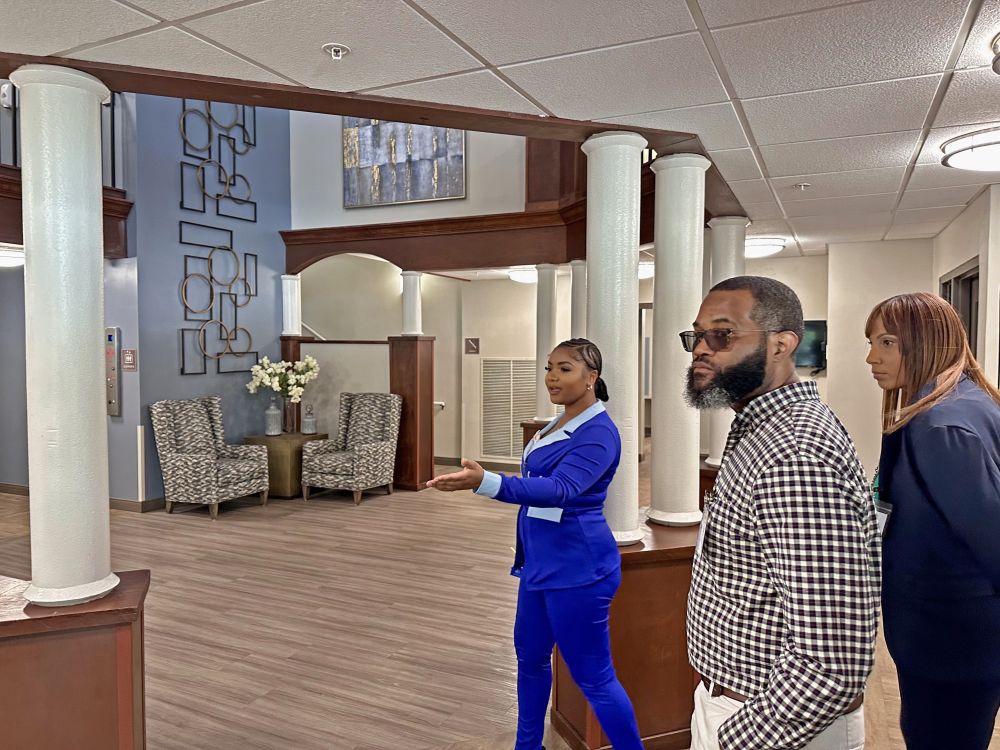A woman guides a man and woman through a newly renovated reception area.
