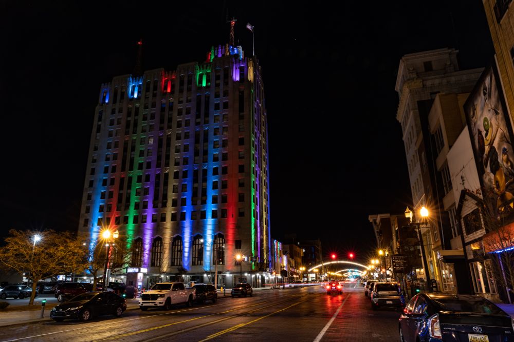 The Mott Foundation building is shown at night from street level, lit in columns of multicolored lights.