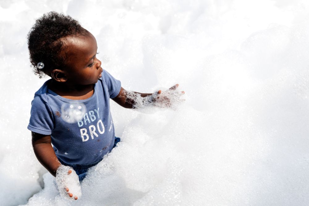 A baby plays in a field of bubbles.