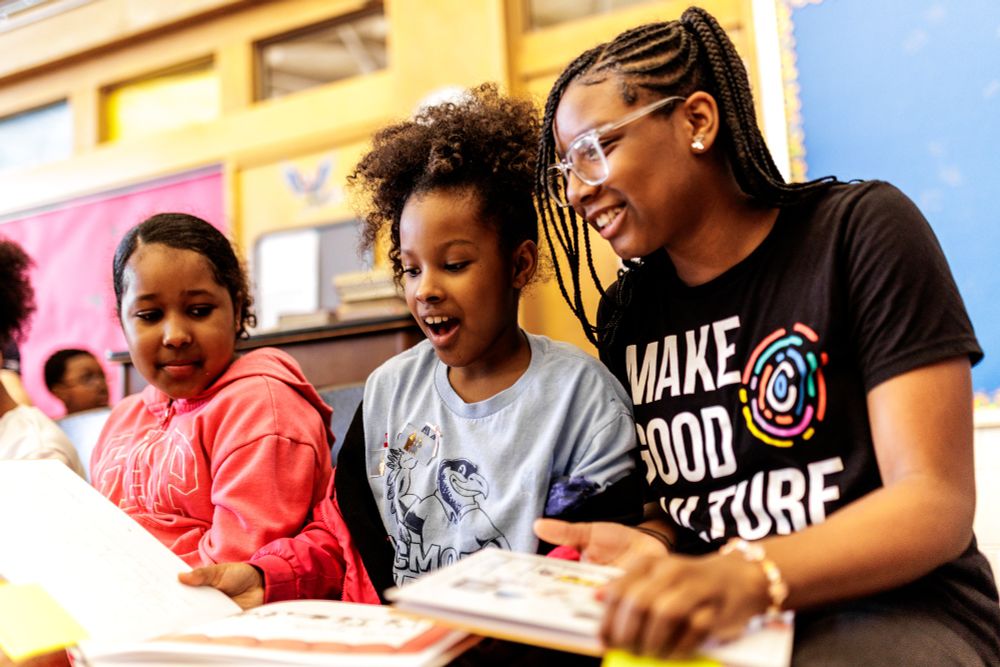 A group of kids excitedly look at the books they are reading.