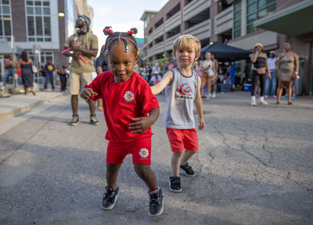A young girl and boy play for the camera at an outdoor festival.