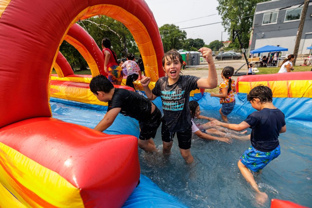 Children enthusiastically play in a colorful inflatable water slide.