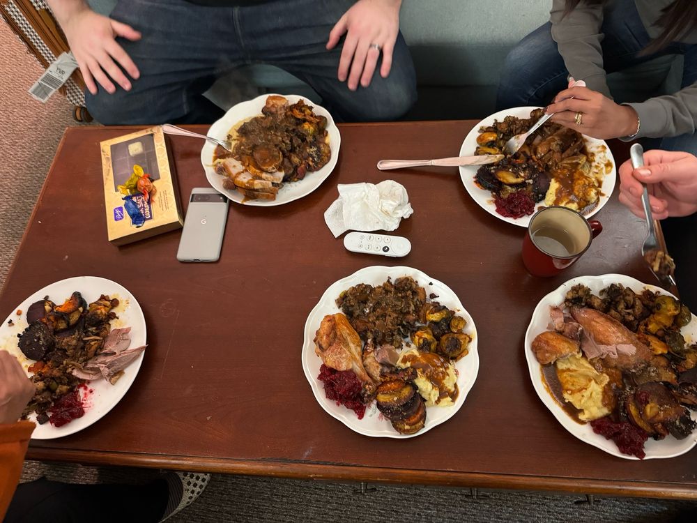 Five plates piled high with turkey dinner on the table